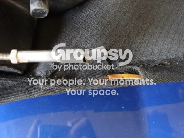 The cable end and adjuster at the slot in the hood, with the old fixing parts lying loose below