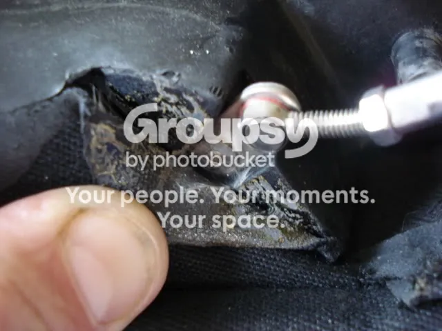 A flap of black hood fabric peeled back to show the securing bolt, with a small Allen key in it
