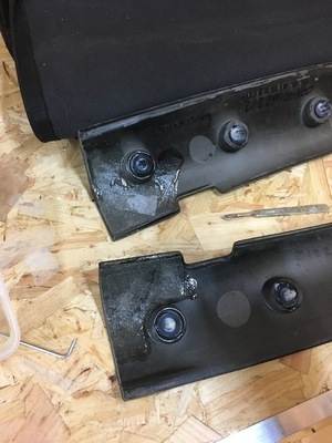 Two hood support pieces on a workbench with the corners repaired and the spigots visible