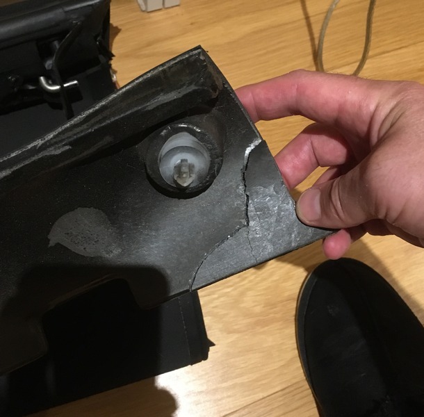 A split corner of the black side pad, held in a hand, with a white spigot cover visible in a recess