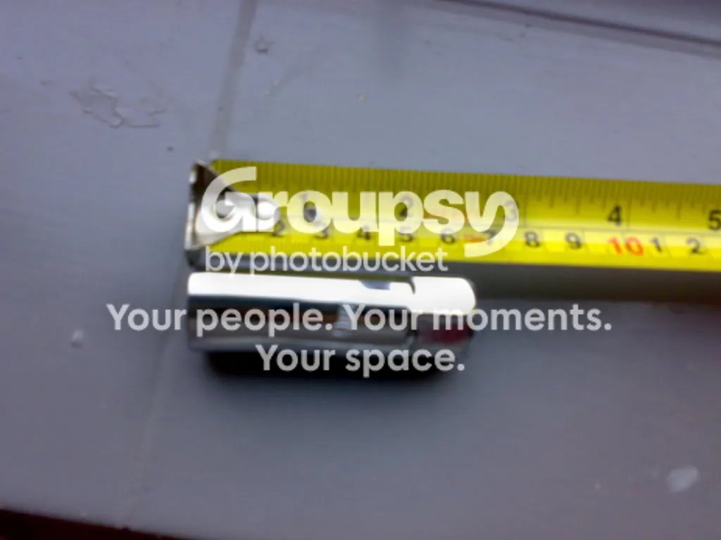 A deep spark plug socket lying next to a tape measure