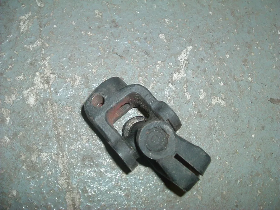 A single dark universal joint lying on a concrete floor