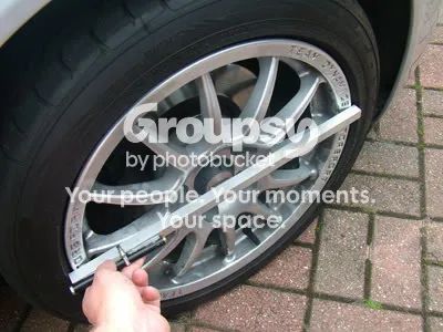 The aluminium channel held across the rim of a front wheel with a hand at the centre