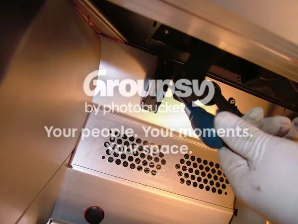 A gloved hand holding a screwdriver up under the dash to line up the rack bolt hole
