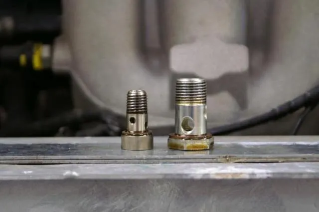 Two clean union fittings standing on a metal bar in front of the inlet manifold