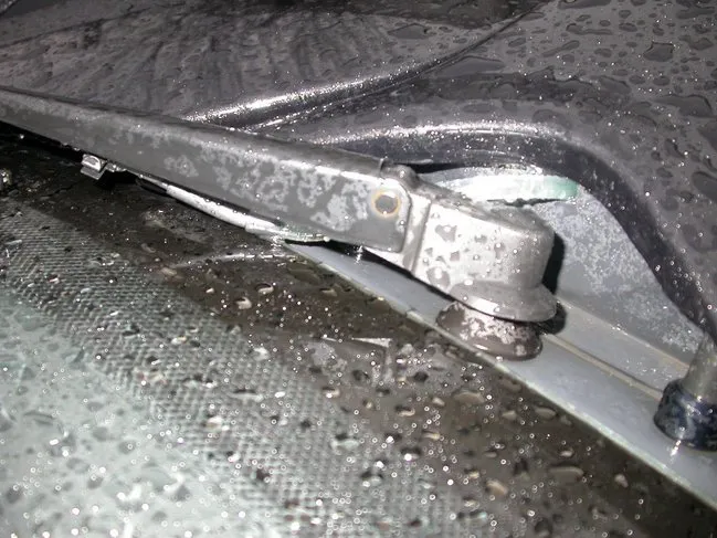 Close-up of the base of a wiper arm with a black spray bar fitted to it