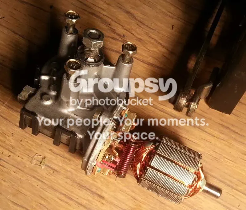 A wiper motor armature with copper commutator and brush gear on a wooden surface