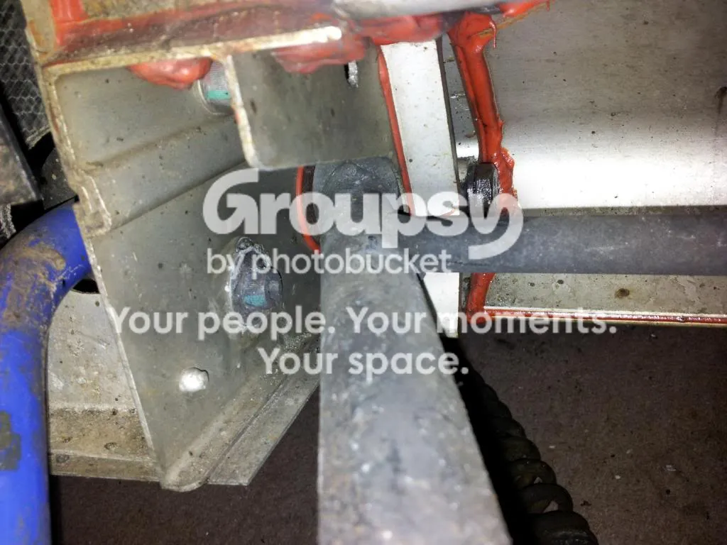 The alloy bracket and bolt at the lower wishbone mounting with the anti-roll bar close by