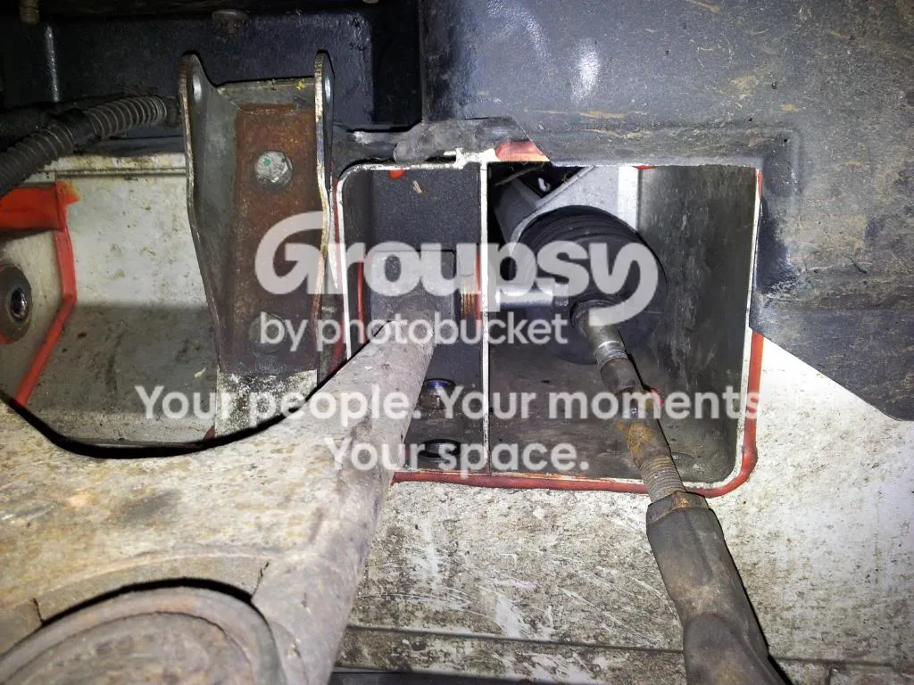 Looking up behind the front wheel arch at the rearmost upper wishbone pivot bolt, with the steering rack gaiter and the steering arm close by